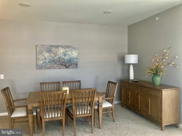 dining area with baseboards and light carpet