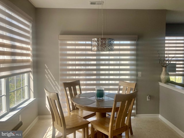 tiled dining area with baseboards, visible vents, and a notable chandelier