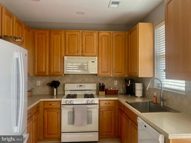 kitchen featuring a sink, white appliances, light countertops, tasteful backsplash, and visible vents