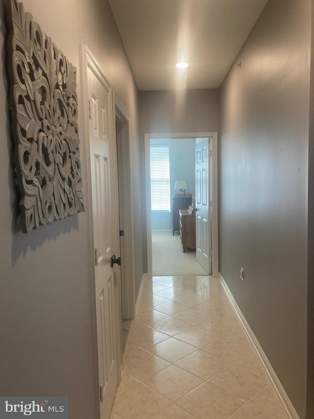 hallway with light tile patterned floors and baseboards