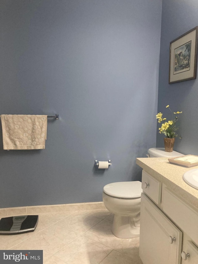 half bathroom with toilet, baseboards, and vanity