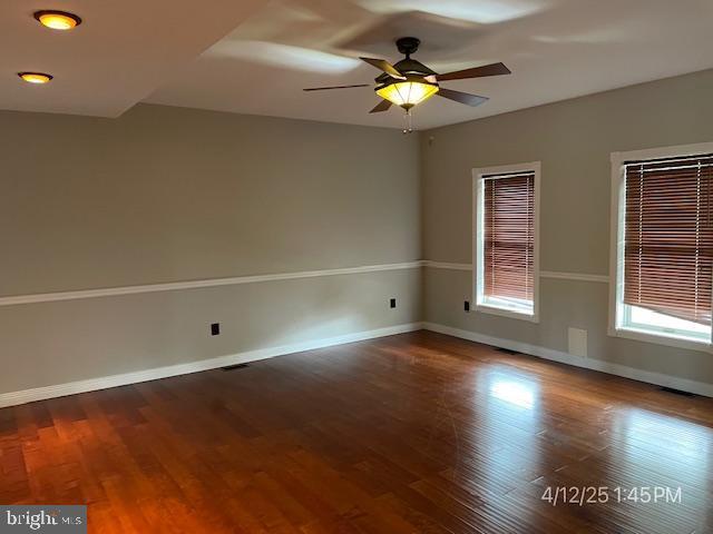 spare room with baseboards, a ceiling fan, and wood finished floors