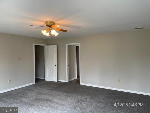 empty room with baseboards, a ceiling fan, dark colored carpet, and visible vents