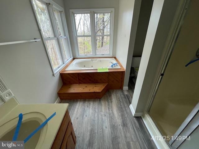 bathroom featuring a whirlpool tub, baseboards, wood finished floors, and vanity
