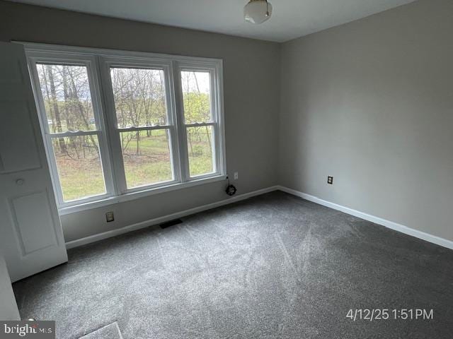 unfurnished room featuring baseboards and dark colored carpet