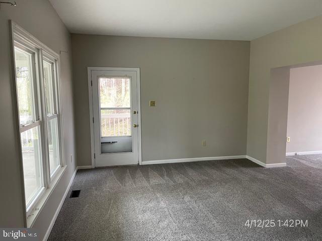 carpeted spare room featuring visible vents, baseboards, and a healthy amount of sunlight