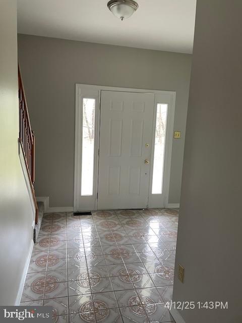 foyer with light tile patterned flooring, baseboards, and stairway