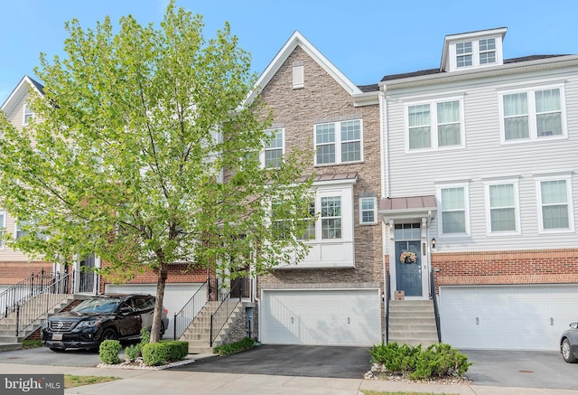 townhome / multi-family property with an attached garage, driveway, and stairs