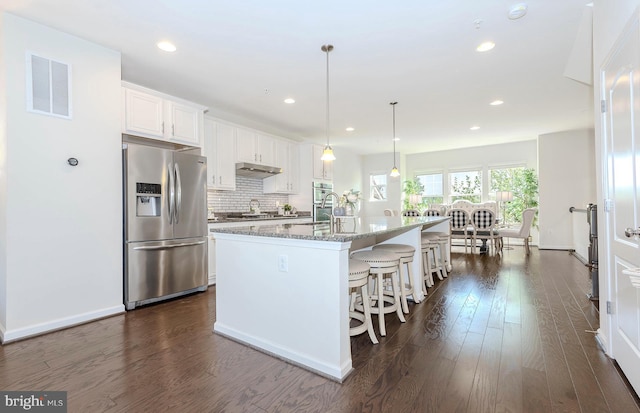 kitchen featuring visible vents, a kitchen island with sink, dark wood-style floors, under cabinet range hood, and appliances with stainless steel finishes