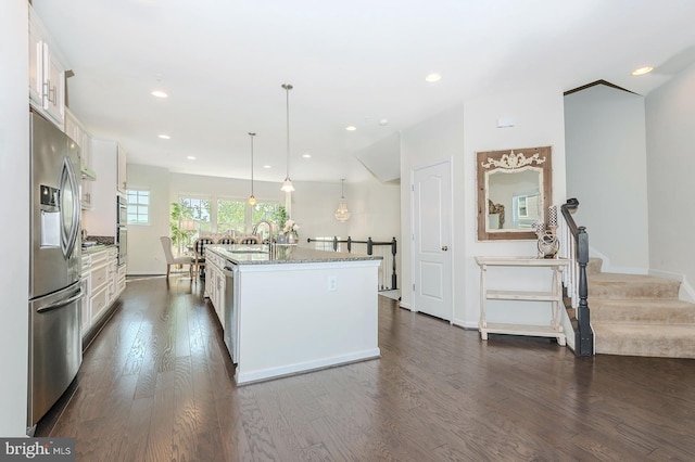 kitchen with dark wood-style flooring, a sink, stainless steel appliances, white cabinetry, and an island with sink