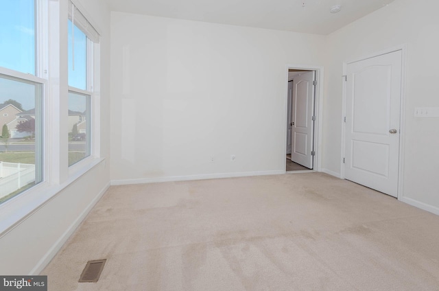 carpeted spare room featuring baseboards and visible vents