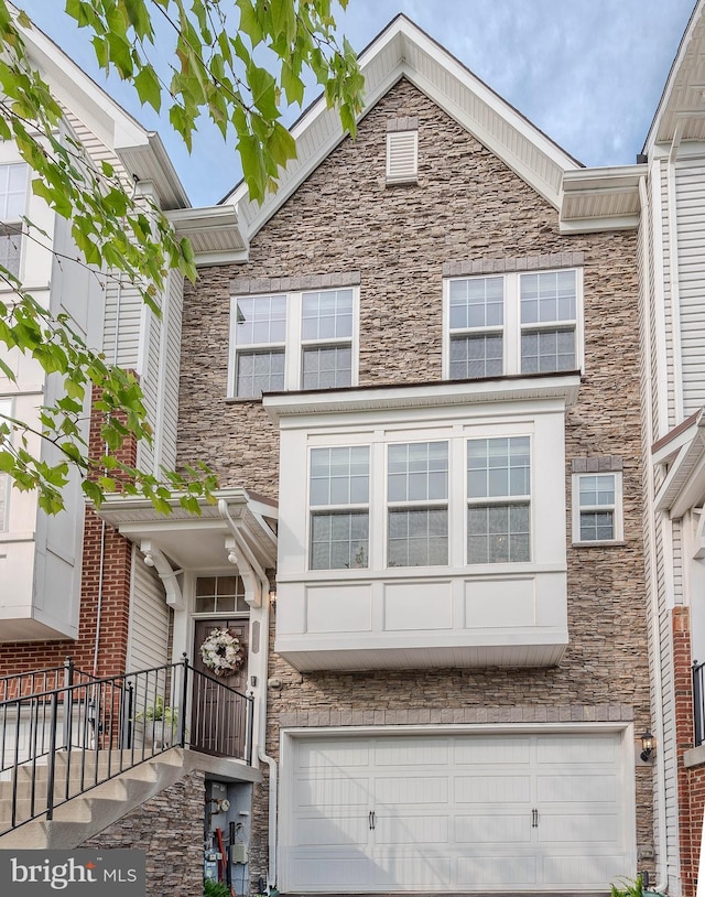 multi unit property with an attached garage, driveway, and stone siding