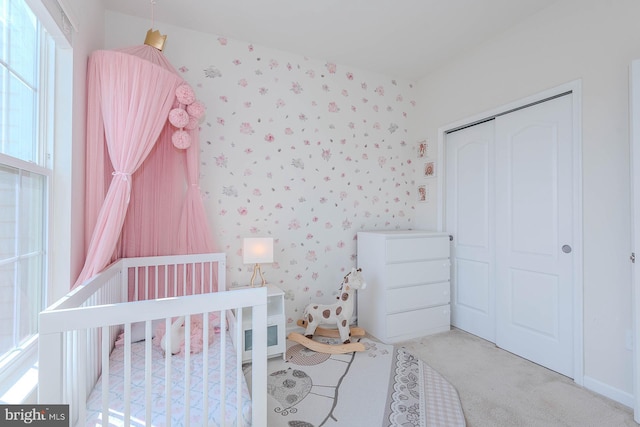 bedroom featuring a closet, carpet flooring, a crib, and wallpapered walls