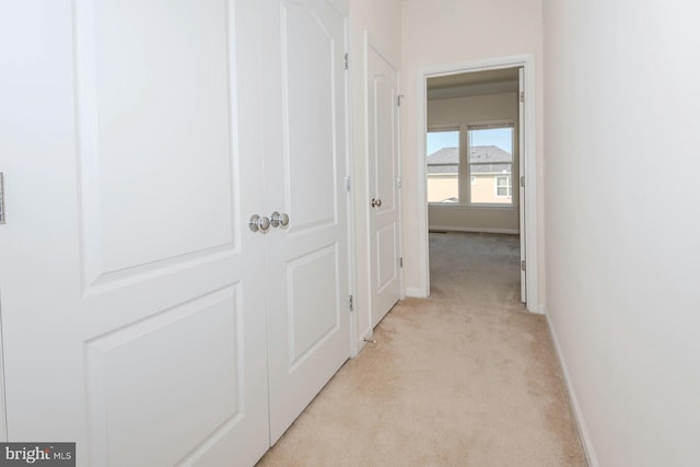 hallway featuring baseboards and light colored carpet