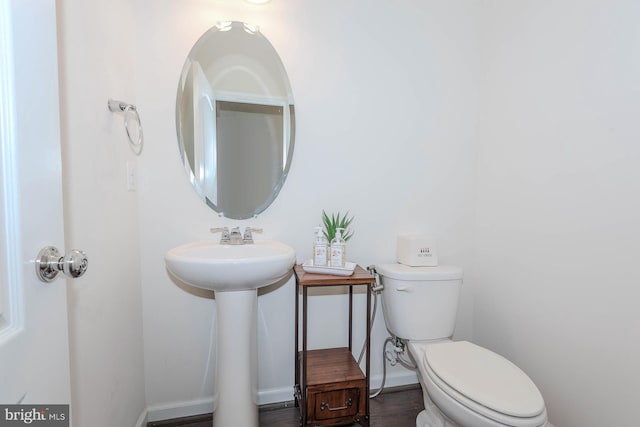 half bath with baseboards, a sink, and toilet