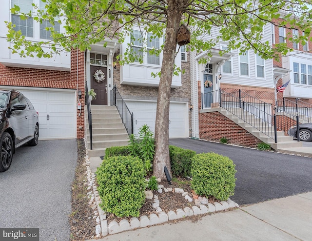 townhome / multi-family property with brick siding, an attached garage, and driveway