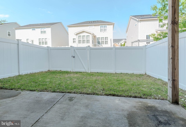 view of yard featuring a patio, a residential view, a gate, and a fenced backyard