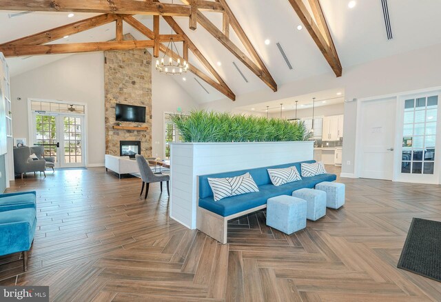 living room with a notable chandelier, beam ceiling, high vaulted ceiling, a stone fireplace, and visible vents