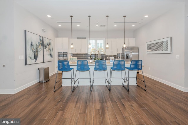 kitchen with a breakfast bar area, dark wood-style floors, a center island, white cabinetry, and stainless steel fridge with ice dispenser