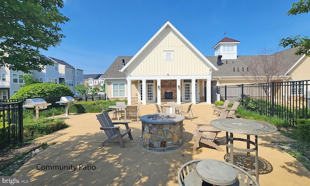 back of house featuring a patio, board and batten siding, a fire pit, and fence