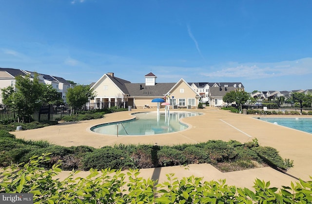 community pool with fence, a patio area, and a residential view