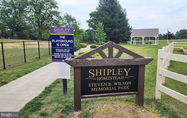 community / neighborhood sign with a yard and fence