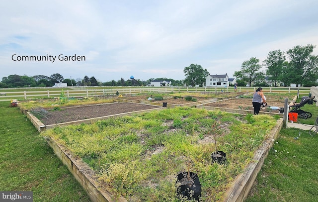 view of yard with fence, a vegetable garden, and a rural view