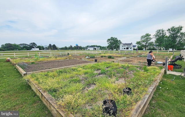 view of yard with fence, a garden, and a rural view