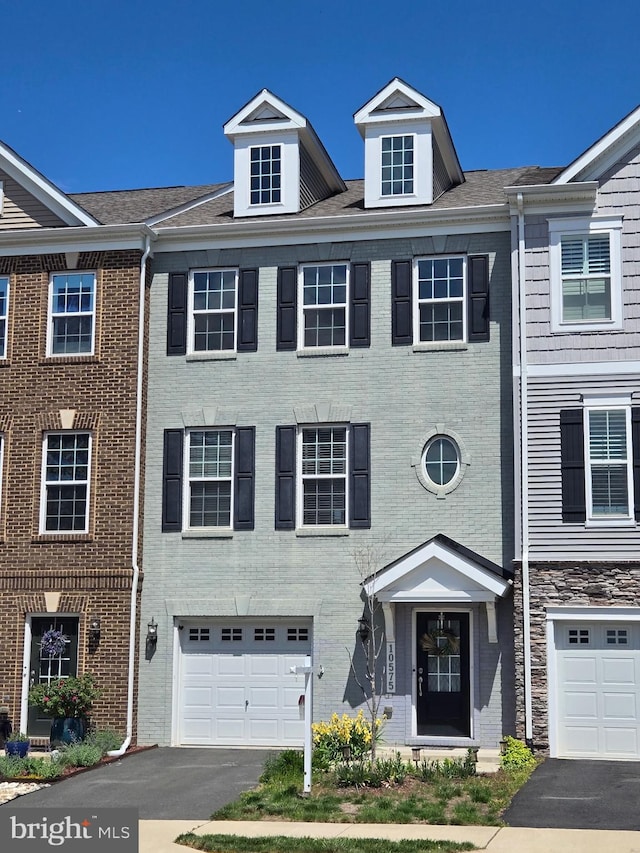 multi unit property featuring an attached garage, driveway, and brick siding