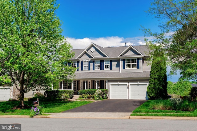 view of front of house featuring asphalt driveway, an attached garage, and roof with shingles