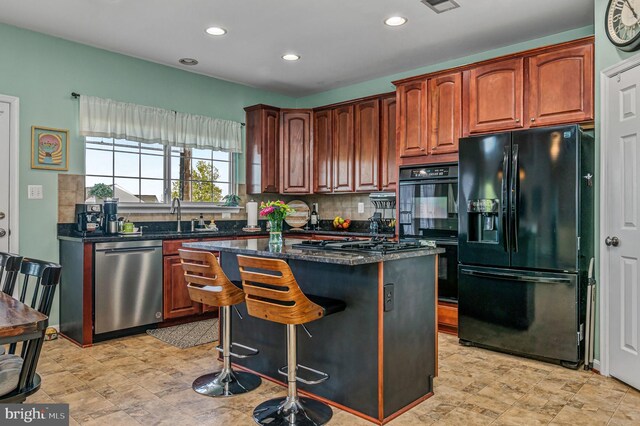 kitchen with black appliances, a sink, tasteful backsplash, recessed lighting, and a kitchen island