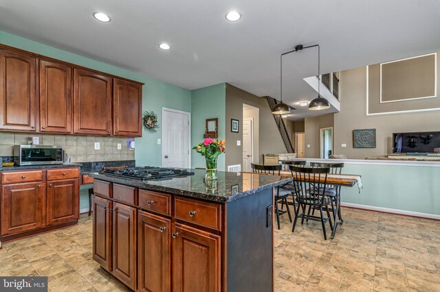 kitchen featuring black gas stovetop, a center island, backsplash, stone finish flooring, and recessed lighting