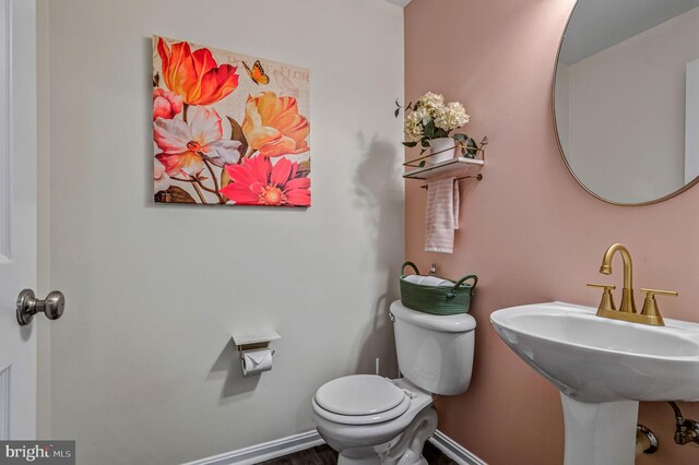 bathroom with toilet, baseboards, and a sink