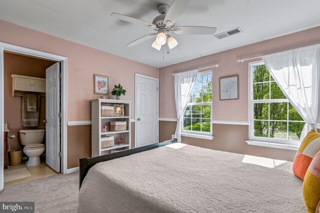 bedroom with carpet flooring, baseboards, ensuite bathroom, and a ceiling fan