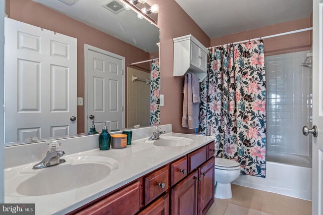 bathroom featuring toilet, double vanity, and shower / bath combo with shower curtain