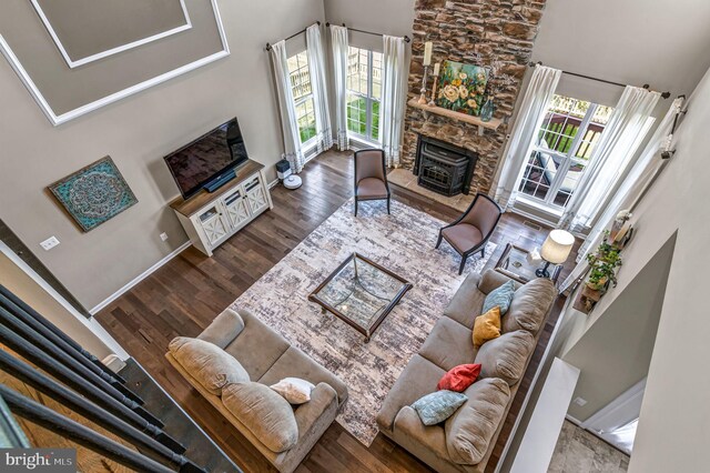 living area with a high ceiling, wood finished floors, healthy amount of natural light, and a fireplace