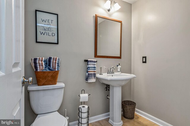 half bath with baseboards and toilet