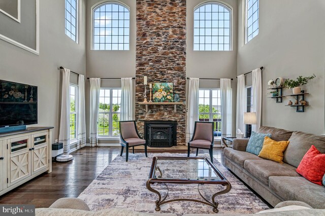 living room featuring a high ceiling, dark wood-style floors, and a wood stove