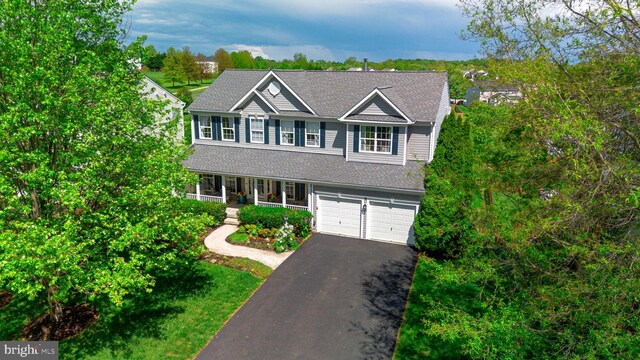traditional-style home with a porch, driveway, a garage, and a shingled roof