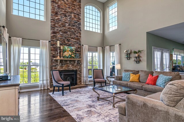 living area featuring a towering ceiling, healthy amount of natural light, dark wood finished floors, and a fireplace