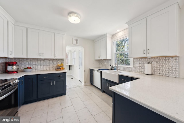 kitchen featuring white cabinets, appliances with stainless steel finishes, a sink, and tasteful backsplash
