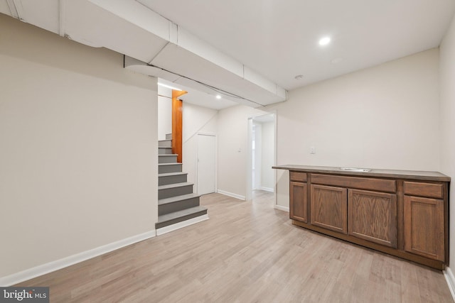 finished basement featuring stairway, baseboards, recessed lighting, and light wood-style flooring