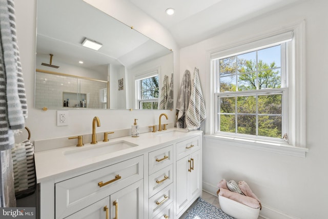 full bathroom featuring a sink, baseboards, a stall shower, and double vanity