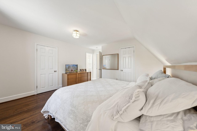 bedroom featuring dark wood-type flooring, baseboards, and vaulted ceiling
