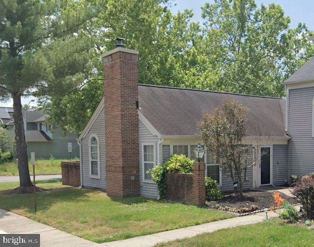 view of front of property featuring a front lawn, roof with shingles, and a chimney