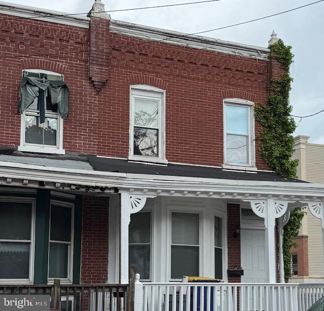 view of side of home with brick siding and a porch