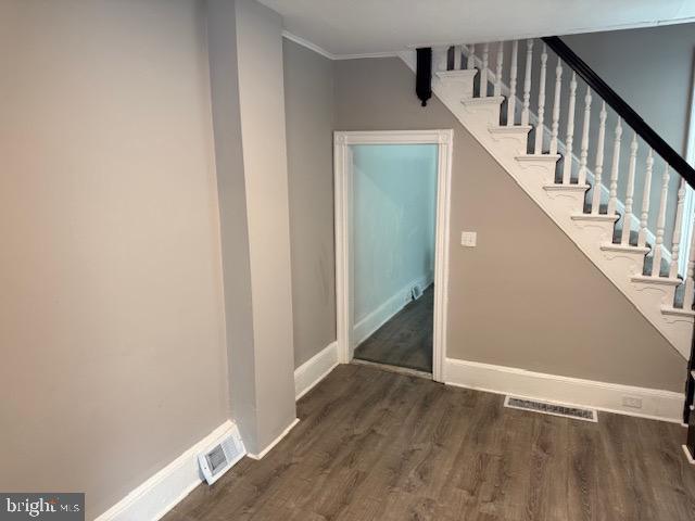 stairs with visible vents, baseboards, crown molding, and wood finished floors