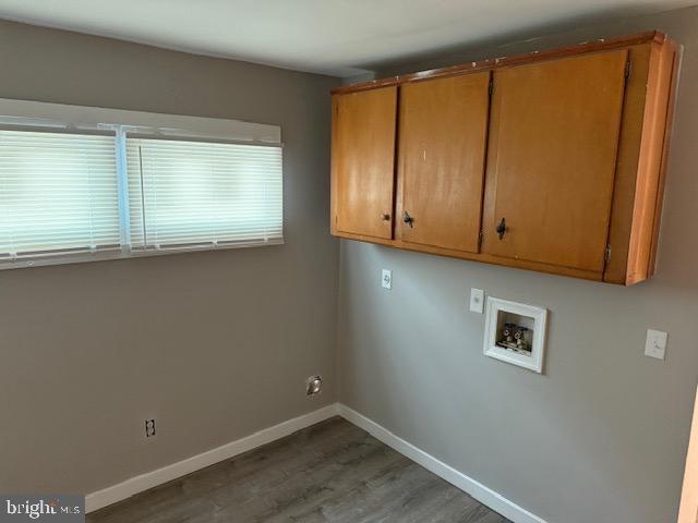 laundry area featuring baseboards, hookup for a washing machine, cabinet space, and wood finished floors