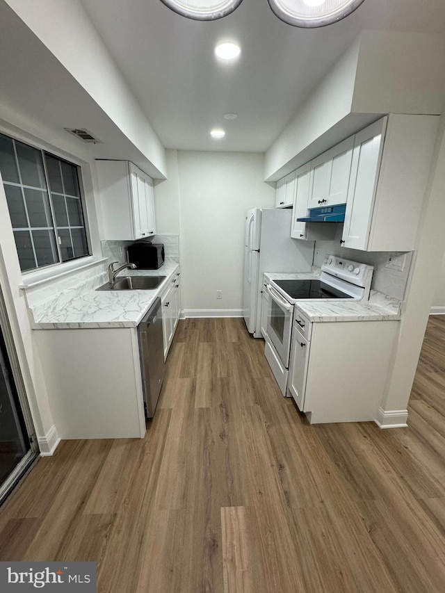 kitchen featuring a sink, light wood-style floors, electric stove, stainless steel dishwasher, and under cabinet range hood