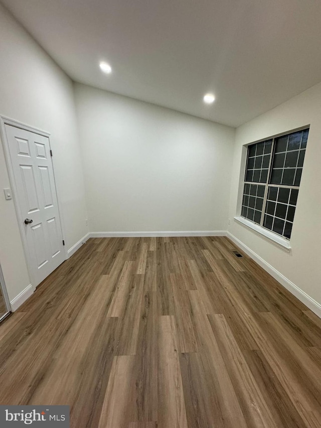 empty room with baseboards, recessed lighting, wood finished floors, and visible vents